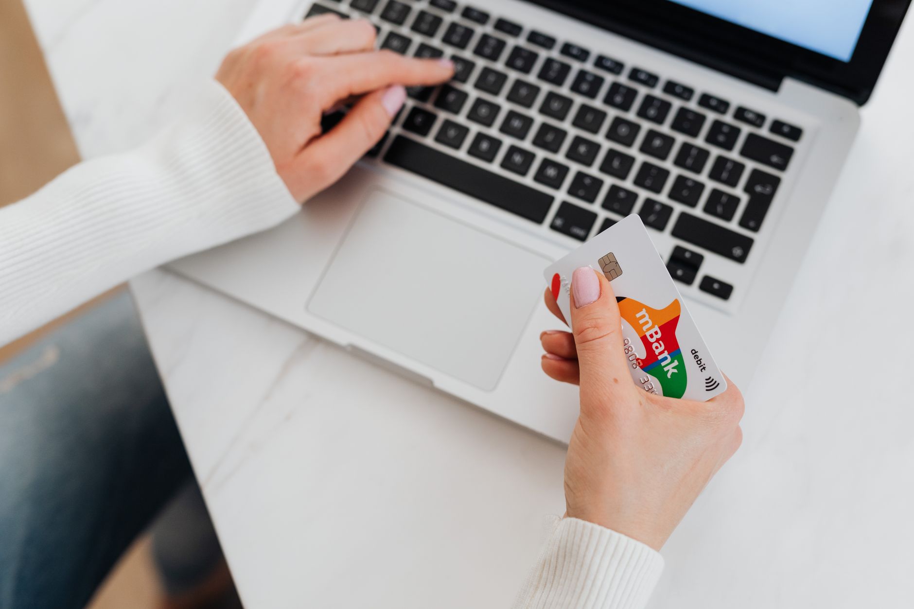 a person changing an online banking password on a laptop while holding a bank card